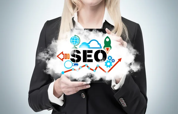 Blonde businesswoman is holding a cloud as a metaphor of 'SEO' — Stock Photo, Image