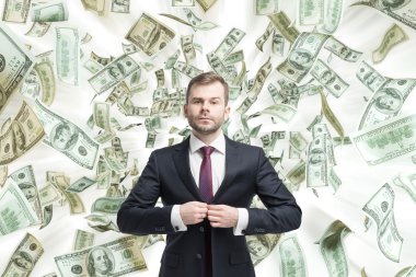 Young handsome businessman is standing over the falling down dollar notes. A concept of career success. clipart