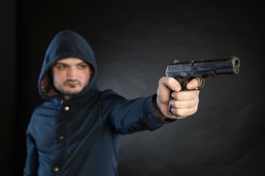 Armed man in a hoodie is pointing a handgun at the target.