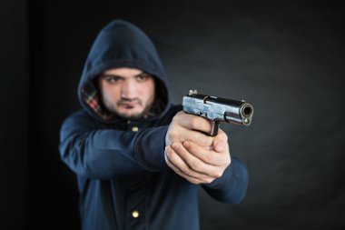 Armed man in a hoodie is pointing a handgun at the target.