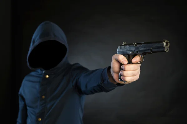 Una persona armada con una sudadera con capucha apunta con una pistola al objetivo. . — Foto de Stock