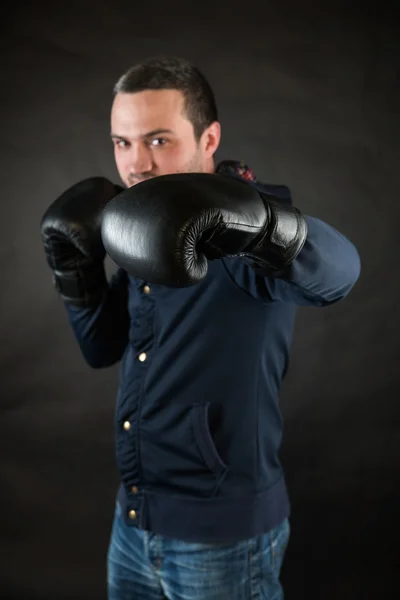 Un bell'uomo con dei guanti da boxe neri. Un concetto di sfida . — Foto Stock