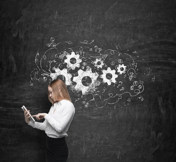 Young beautiful business woman is thinking about business optimisation process by working on the tablet. Drawn business flowchart on the concrete wall. — Stock Photo, Image