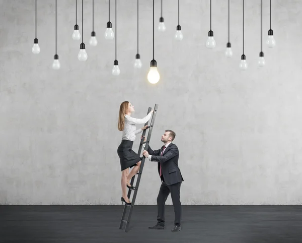 Un homme d'affaires tient une échelle pour la femme d'affaires. Le concept de travail d'équipe et de coopération . — Photo