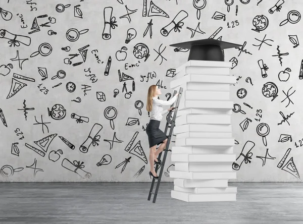 Jonge dame is klimmen tot krijgen universitair diploma. Stapel boeken en een hoed afstuderen als een prijs. — Stockfoto