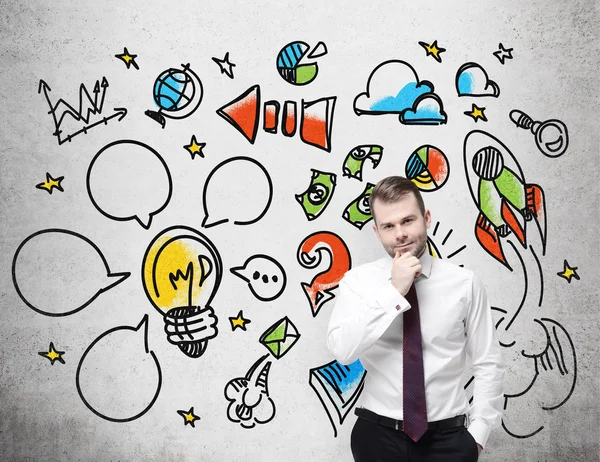 Confident businessman is thinking about how to create and develop business project. A sketch of the business icons on the wall. — Stock Photo, Image