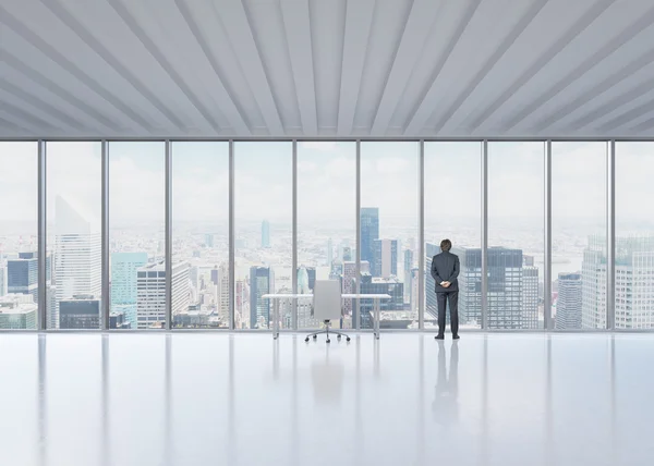 Rear view of the businessman who looks out the window in New York's panoramic office. A concept of the modern workplace. — Stock Photo, Image