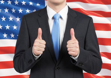 Bir kişi bir takım elbise içinde Yaşasın. Arka plan olarak Amerika Birleşik Devletleri bayrağı.