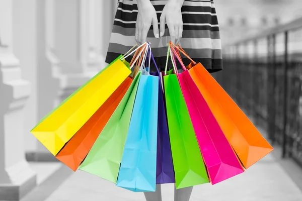 Vrouw met kleurrijke shopping tassen in het winkelcentrum. Zwarte en witte achtergrond. — Stockfoto