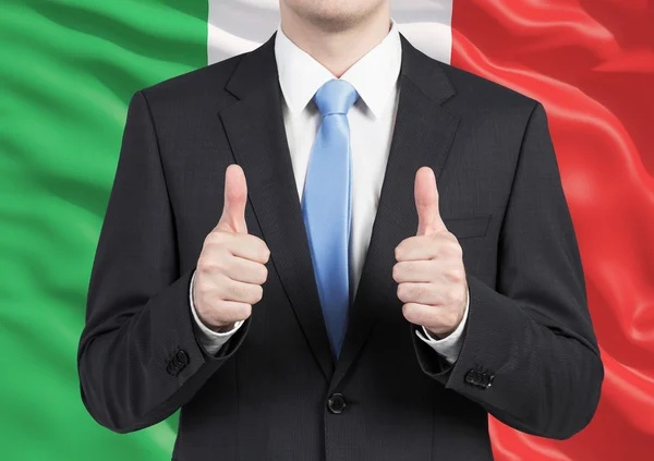 Una persona con traje pulgar hacia arriba. Bandera de Italia como fondo . —  Fotos de Stock