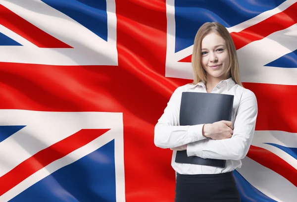 Lächelnde Geschäftsfrau im weißen Hemd mit schwarzem Ordner. Große britische Flagge als Hintergrund. — Stockfoto