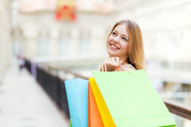 mutlu bir genç kadın ile lüks mağazalardan renkli alışveriş torbaları.