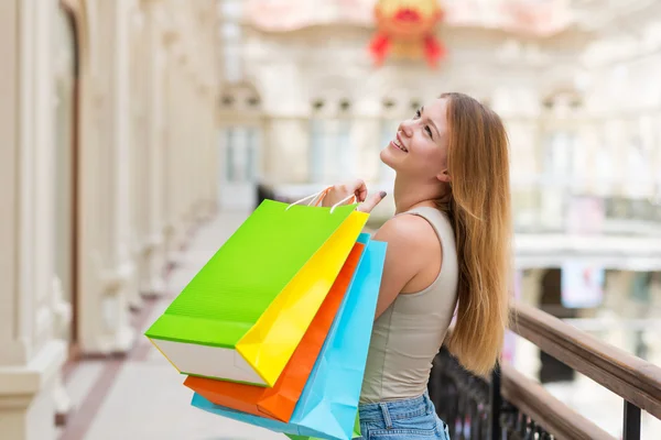 おしゃれな店からカラフルなショッピング バッグを持つ幸せな若い女性. — ストック写真