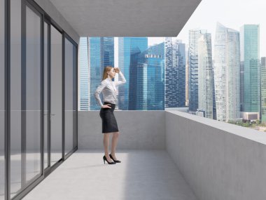 Young business lady is standing on the balcony of the skyscraper and looking at the new business perspectives. Singapore panoramic view.