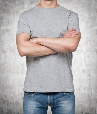 Beton zemin üzerine izole çapraz el ile gri t-shirt giyen adam.