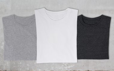 yakın çekim üç t-shirt (siyah, beyaz ve gri). Beton arka plan.