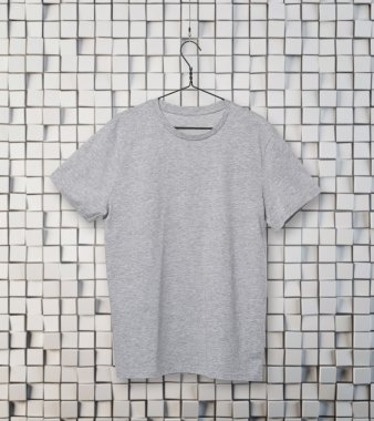 elbise askısı üzerinde gri t-shirt close-up. Mozaik arka plan.