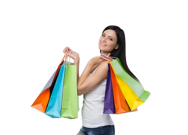 A happy brunette woman with the colourful shopping bags from the fancy shops. Isolated. — Stock Photo, Image