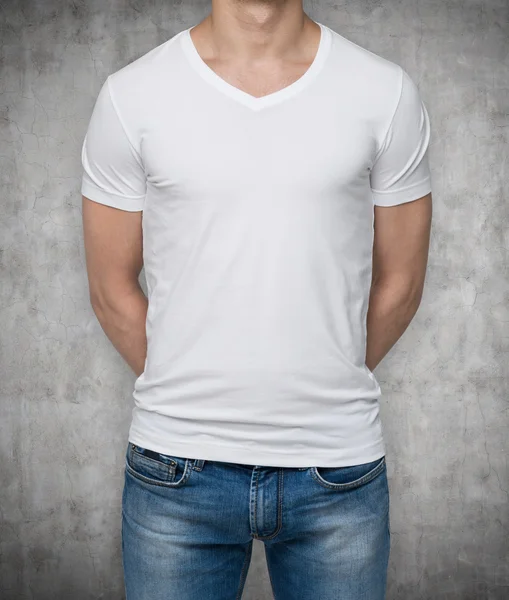 Close up of the body view of the man in a white t-shirt. Hands are crossed behind the back. Concrete background. — Stock Photo, Image