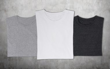 yakın çekim üç t-shirt (siyah, beyaz ve gri). Beton arka plan.