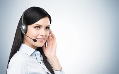 Portrait of smiling cheerful support phone operator in headset. Studio blue background.