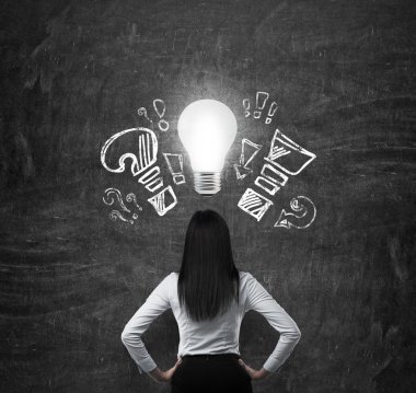 Rear view of the brunette woman in formal clothes. Drawn exclamation, question marks and a light bulb as a symbol of the new business idea.