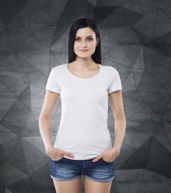 Brunette girl in a white t-shirt and denim shorts. Contemporary dark grey background.