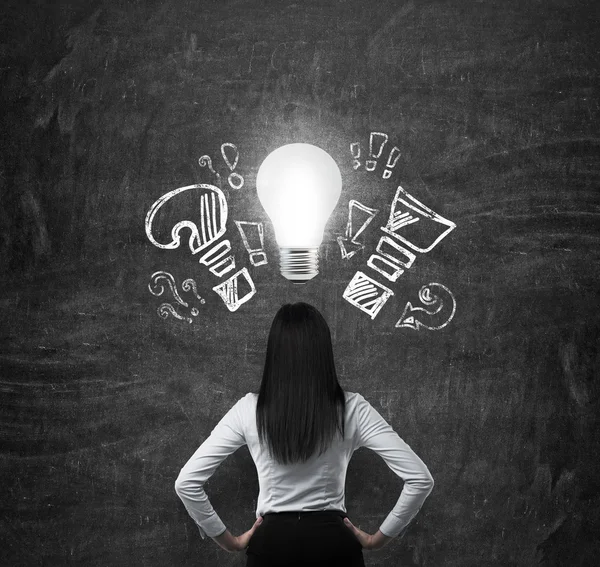 Rear view of the brunette woman in formal clothes. Drawn exclamation, question marks and a light bulb as a symbol of the new business idea. — Stockfoto