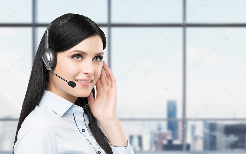 Portrait of smiling cheerful support phone operator in headset. New York panoramic office background.