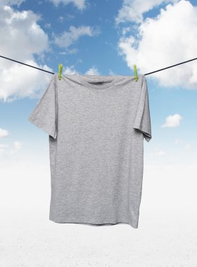 Close up of a grey t-shirts on the rope. Cloudy sky background.
