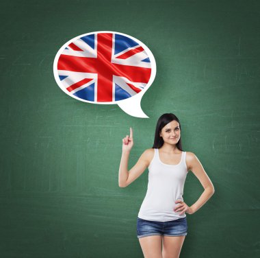 Beautiful woman is pointing out the thought bubble with Great Britain flag. Green chalk board background.