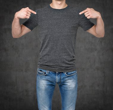 Close-up of a man pointing his fingers on a blank grey t-shirt. Dark concrete background. clipart