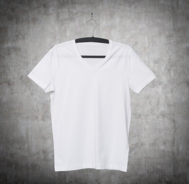 Close up of a V shape white t-shirt on cloth hanger. Concrete background.