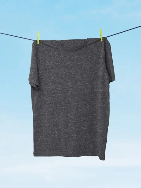 Close up of a dark grey t-shirts on the rope. Cloudy sky background. — Stock Photo, Image