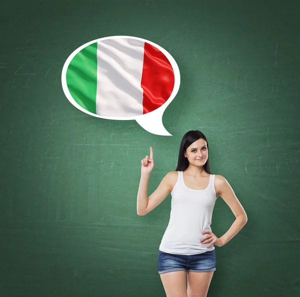 Beautiful woman is pointing out the thought bubble with Italian flag. Green chalk board background. — Zdjęcie stockowe