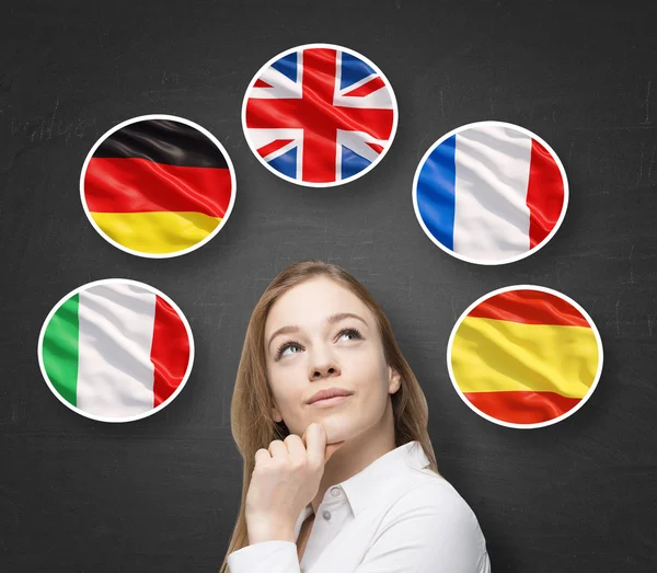 Hermosa dama está rodeada de burbujas con banderas de los países europeos (italiano, alemán, Gran Bretaña, francés, español). Aprendizaje del concepto de lenguas extranjeras. Fondo pizarra . — Foto de Stock