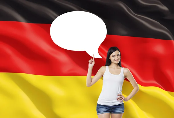 Beautiful woman is pointing out the empty thought bubble. German flag as a background. — Stock fotografie