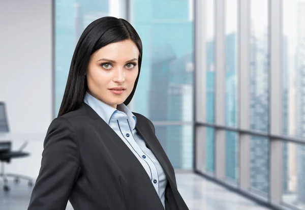 Retrato de una hermosa morena vestida con traje formal. Vista panorámica de la ciudad de negocios desde la oficina moderna . —  Fotos de Stock