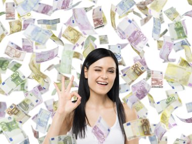 Brunette woman shows ok sign. Euro notes are falling down over isolated background.