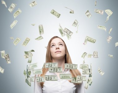 Young lady is looking upward. Dollar notes a falling down from the sky.