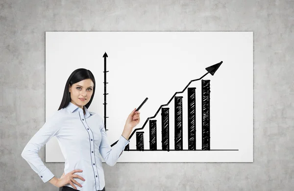 A brunette is pointing out bar chart. A concept of successful business presentation. Concrete wall. — Stok fotoğraf