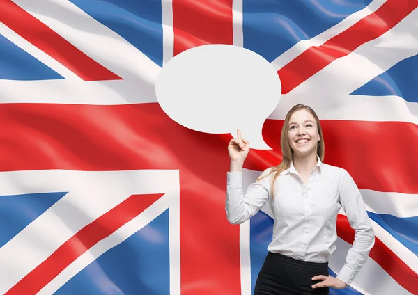 Beautiful woman is pointing out the empty thought bubble. Great Britain flag as a background. — Stockfoto