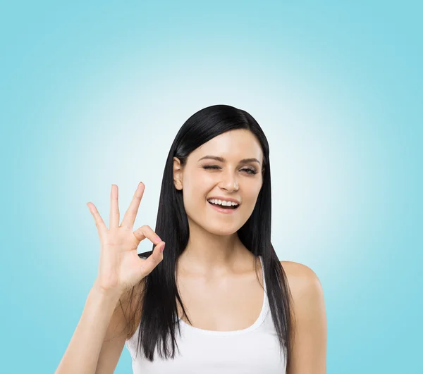 Brunette woman shows ok sign. Blue background. — 스톡 사진