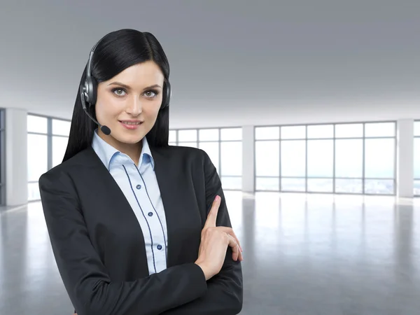 Portrait of brunette support phone operator with the headset. Modern panoramic office space. — Stok fotoğraf