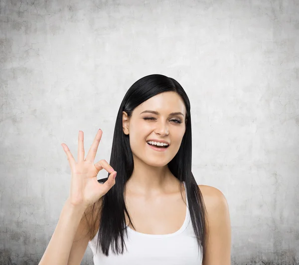 Brunette woman shows ok sign. Concrete background. — 스톡 사진