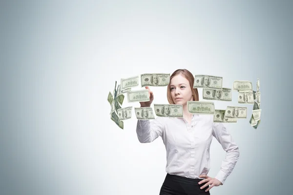 Young lady is controlling cash flow of the dollar notes. Light blue background.n — Stok fotoğraf