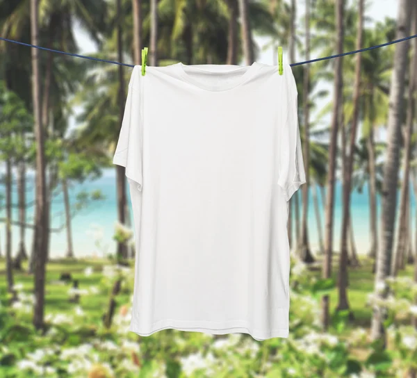 Feche uma camiseta branca na corda. Selvas tropicais e mar em um borrão como fundo . — Fotografia de Stock