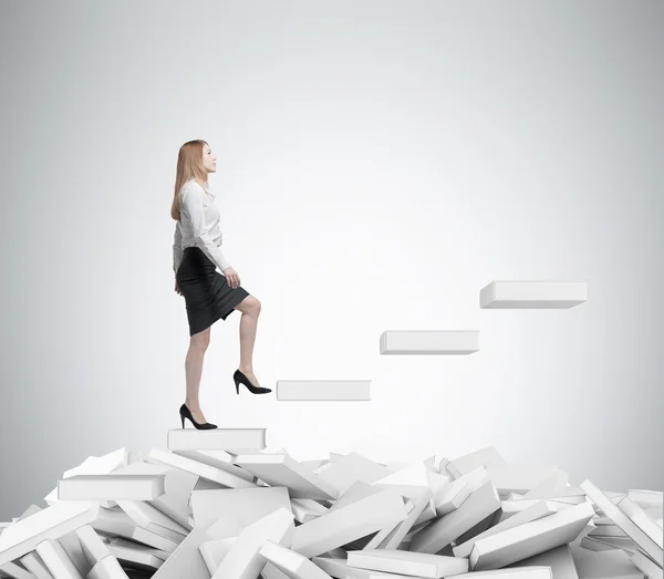 Young business woman is going up to the stairs. A concept of education process. White books on the floor. — Stock Photo, Image