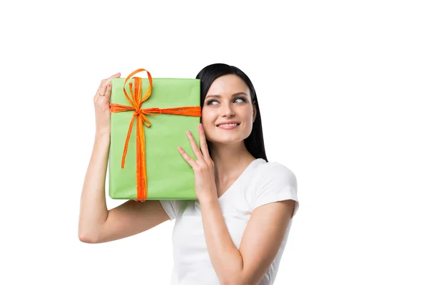 A brunette woman is holding a green gift box. Isolated. — Stockfoto