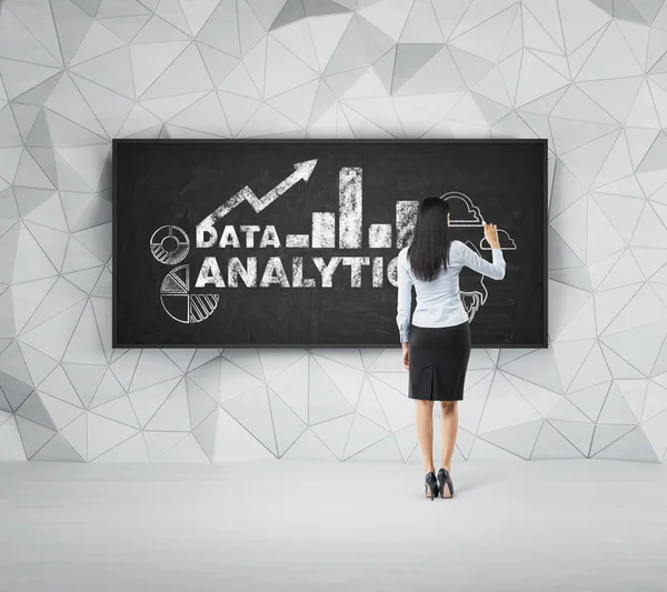 Rear view of full-length brunette woman who is presenting analytical solutions on the black board. — Stock Photo, Image